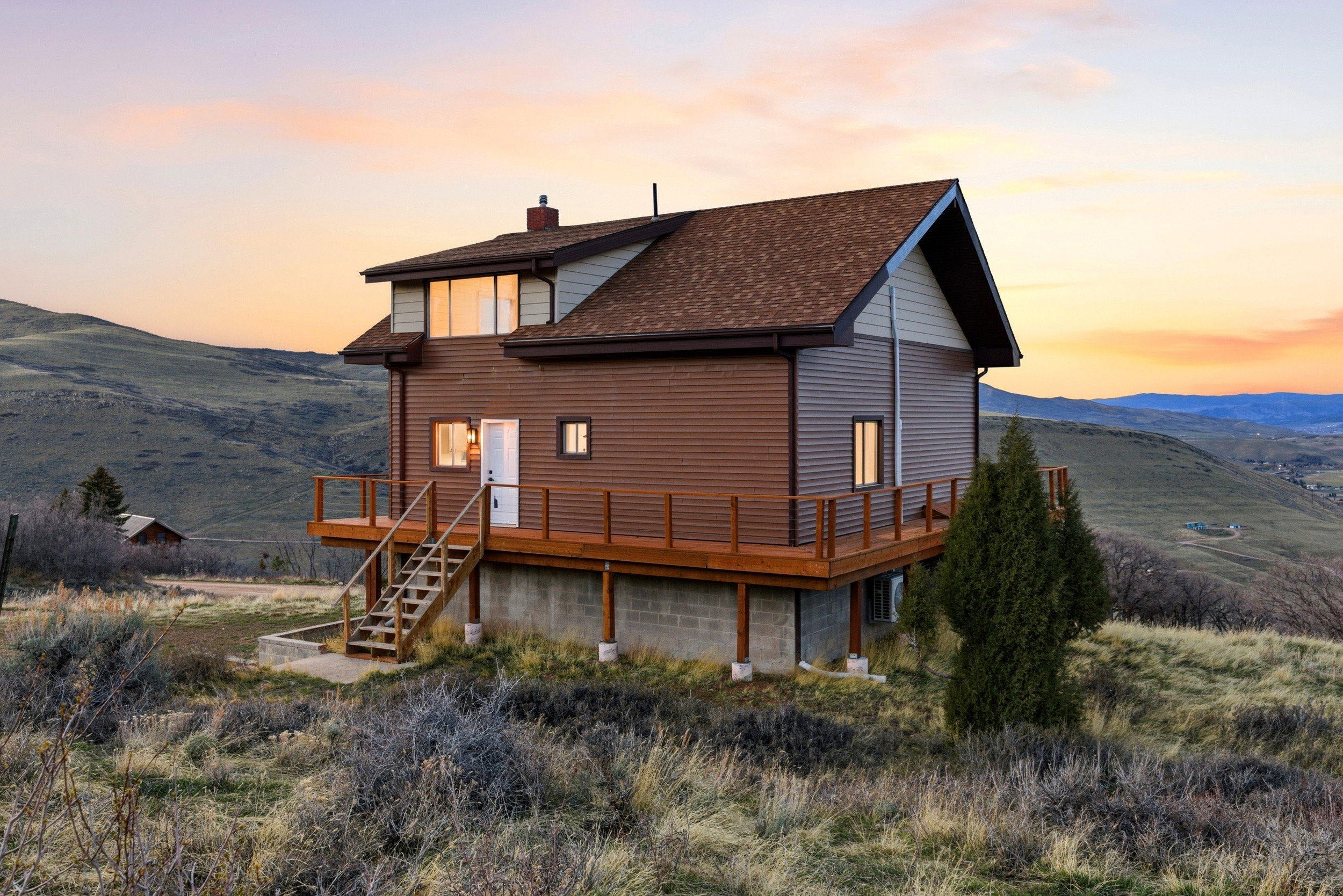 Back of house at dusk with a deck with mountain view, a chimney, and a shingled roof
