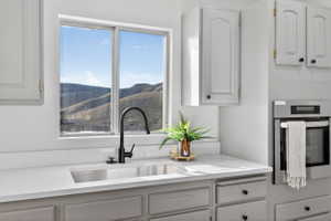 Kitchen with oven, white cabinets, light stone countertops, and a mountain view
