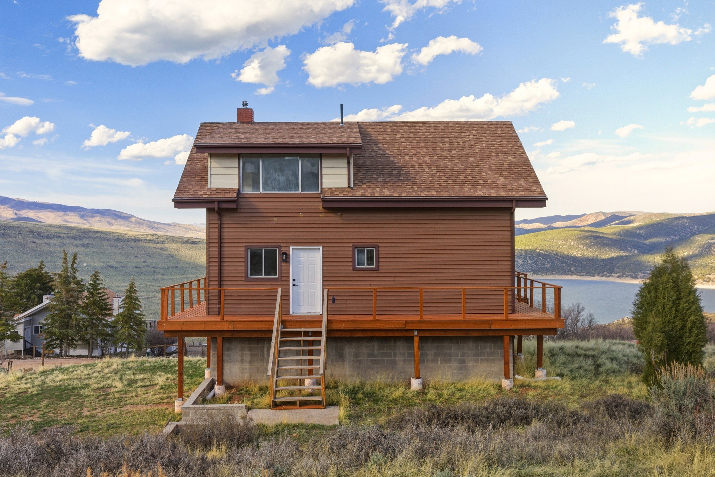 Back of house featuring a deck with mountain view, roof with shingles, and a chimney