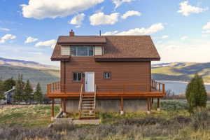 Back of house featuring a deck with mountain view, roof with shingles, and a chimney