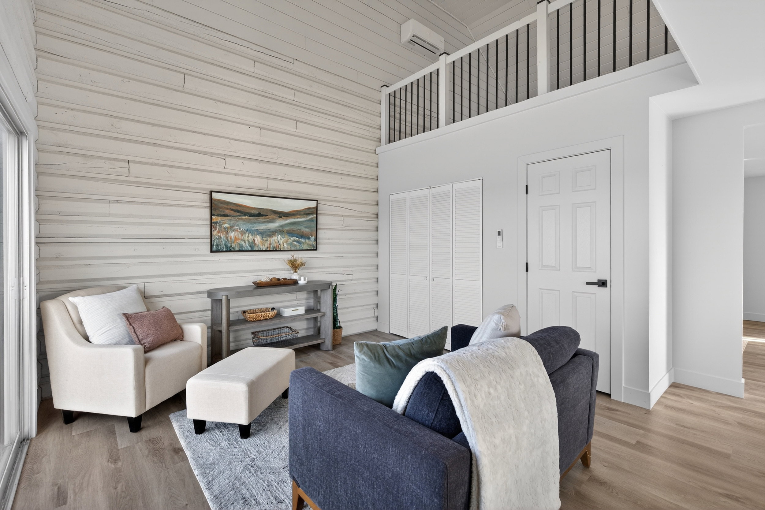 Living area featuring light wood finished floors, a high ceiling, and wooden walls
