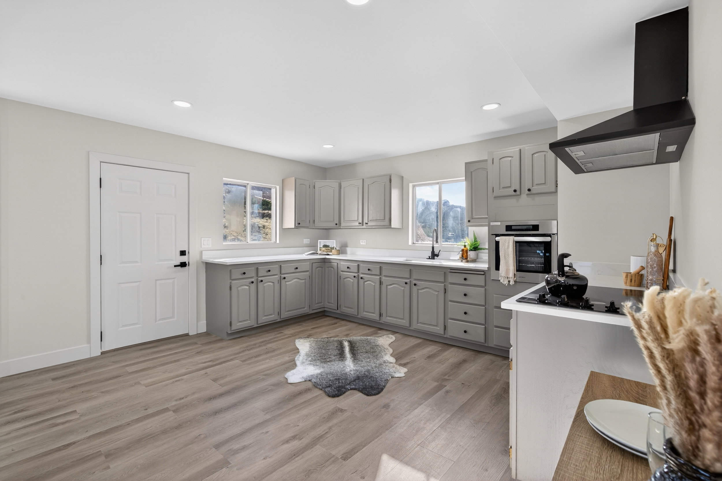 Kitchen with gray cabinets, stainless steel oven, light countertops, light wood finished floors, and recessed lighting