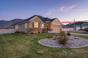 View of front facade, garage, and stucco/stone siding