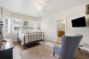 Primary bedroom with wood flooring, ceiling fan, and ensuite bath