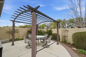 Fenced backyard with a pergola, outdoor dining space, and a patio