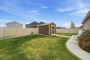 Fenced backyard featuring a storage shed