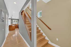 Stairs with wood finished floors and recessed lighting