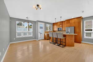 Kitchen with light countertops, wood finish cabinetry, a kitchen bar, a center island, and light wood-type flooring