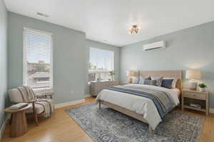 Bedroom featuring light wood finished floors and a wall mounted mini split