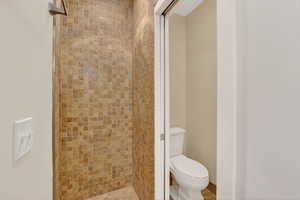 Bathroom featuring walk-in tile shower & enclosed toilet area