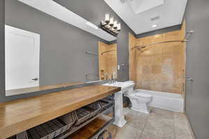 Full bathroom with stone tile flooring and shower / tub combination