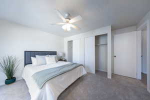 Bedroom with carpet floors, ceiling fan, and a textured ceiling