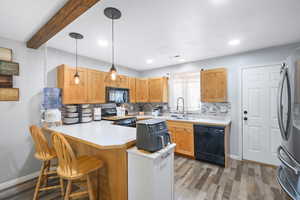 Kitchen with decorative backsplash, light countertops, a peninsula, decorative light fixtures, and a kitchen bar