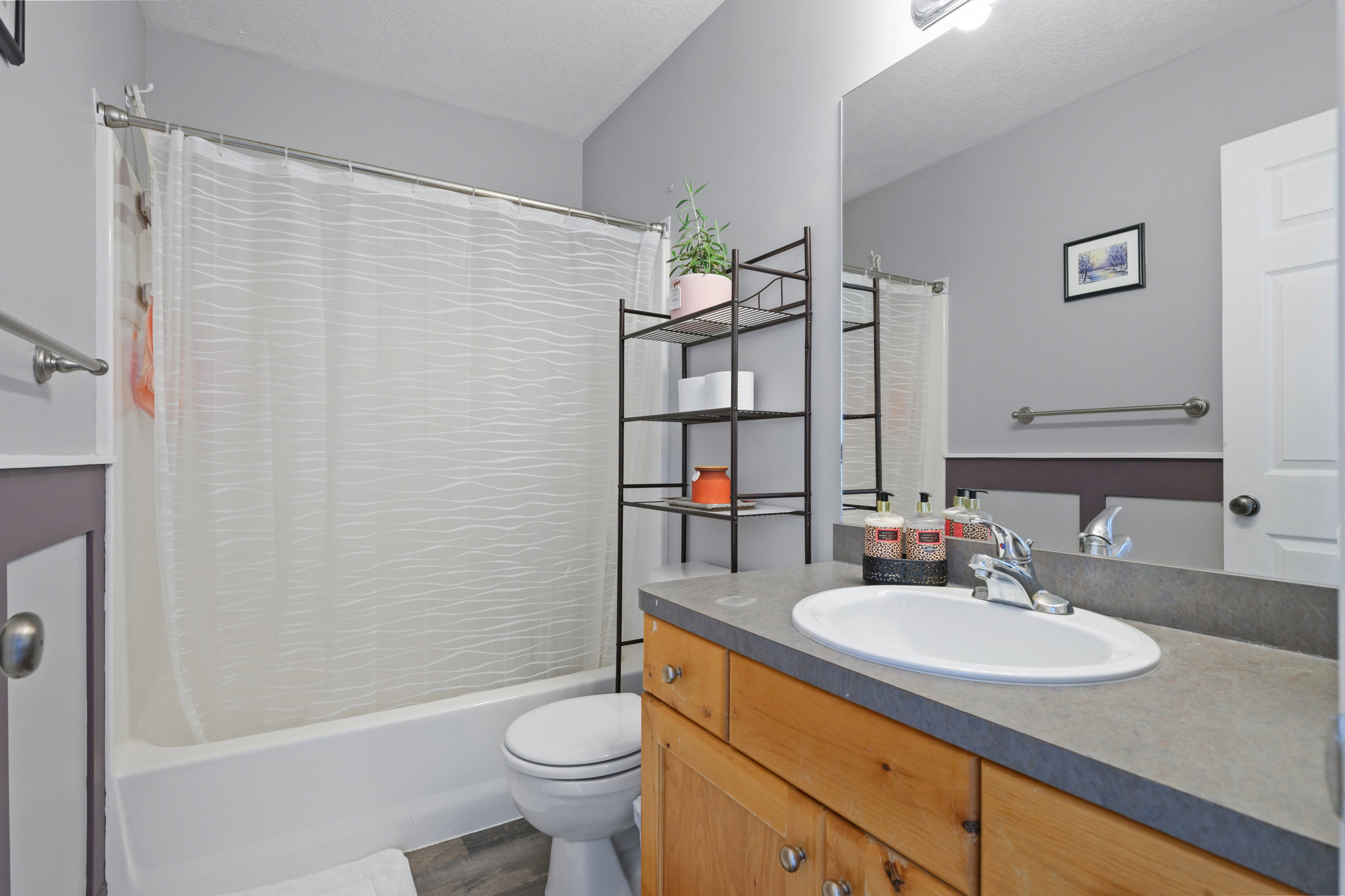 Full bathroom with vanity, shower / tub combo, and dark wood-type flooring