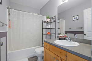 Full bathroom with vanity, shower / tub combo, and dark wood-type flooring