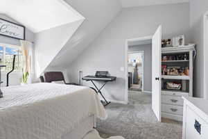 Bedroom with light colored carpet and vaulted ceiling