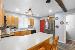 Kitchen with backsplash, a peninsula, light countertops, a kitchen bar, and black appliances
