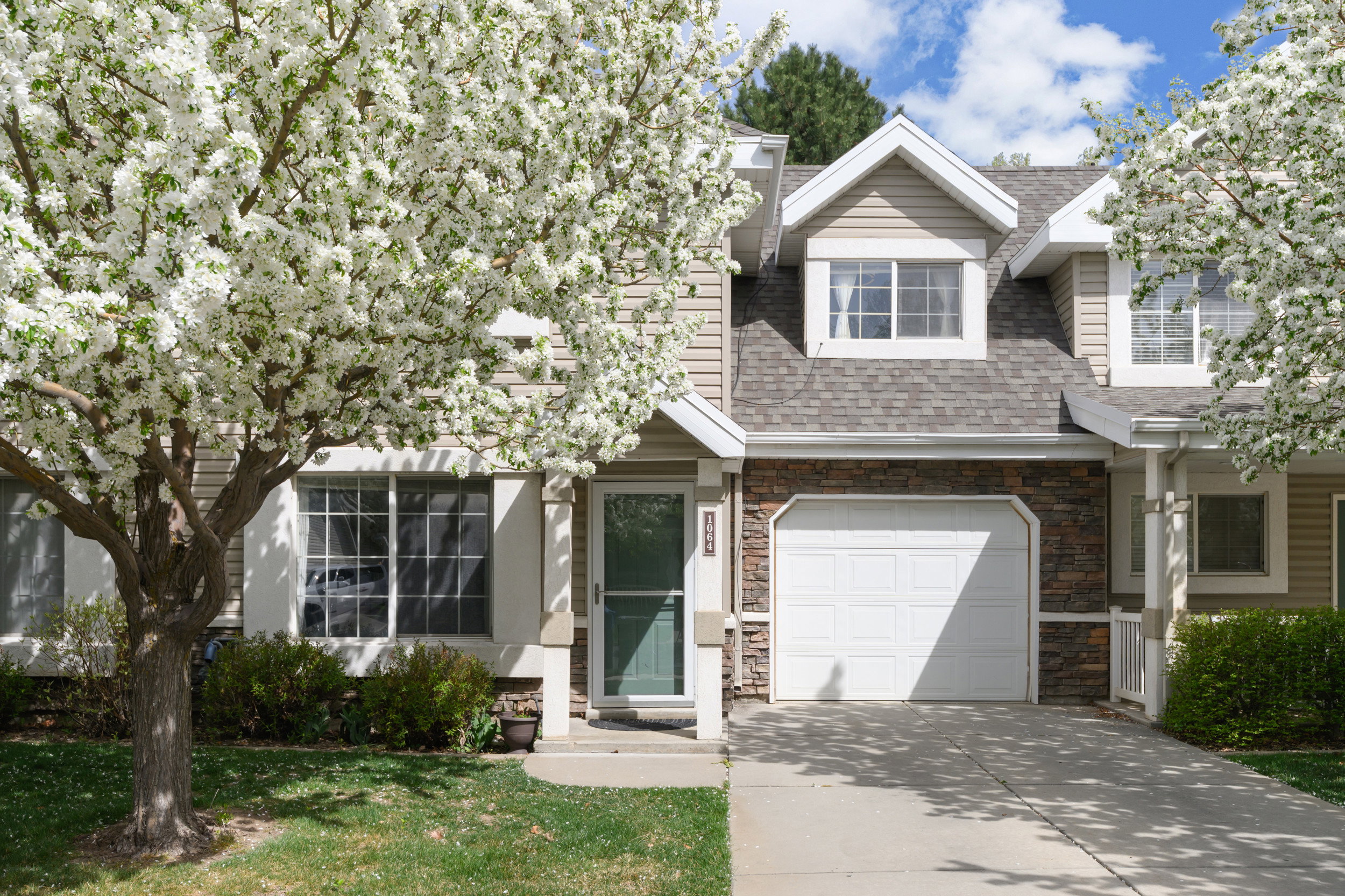 View of front of home with stone siding, driveway, a shingled roof, a garage, and a front yard