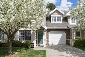 View of front of home with stone siding, driveway, a shingled roof, a garage, and a front yard