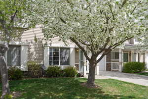 View of front of home with a garage, concrete driveway, a front yard, stone siding, and a porch