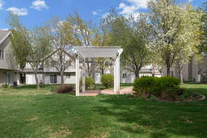 View of green lawn with a residential view and a pergola
