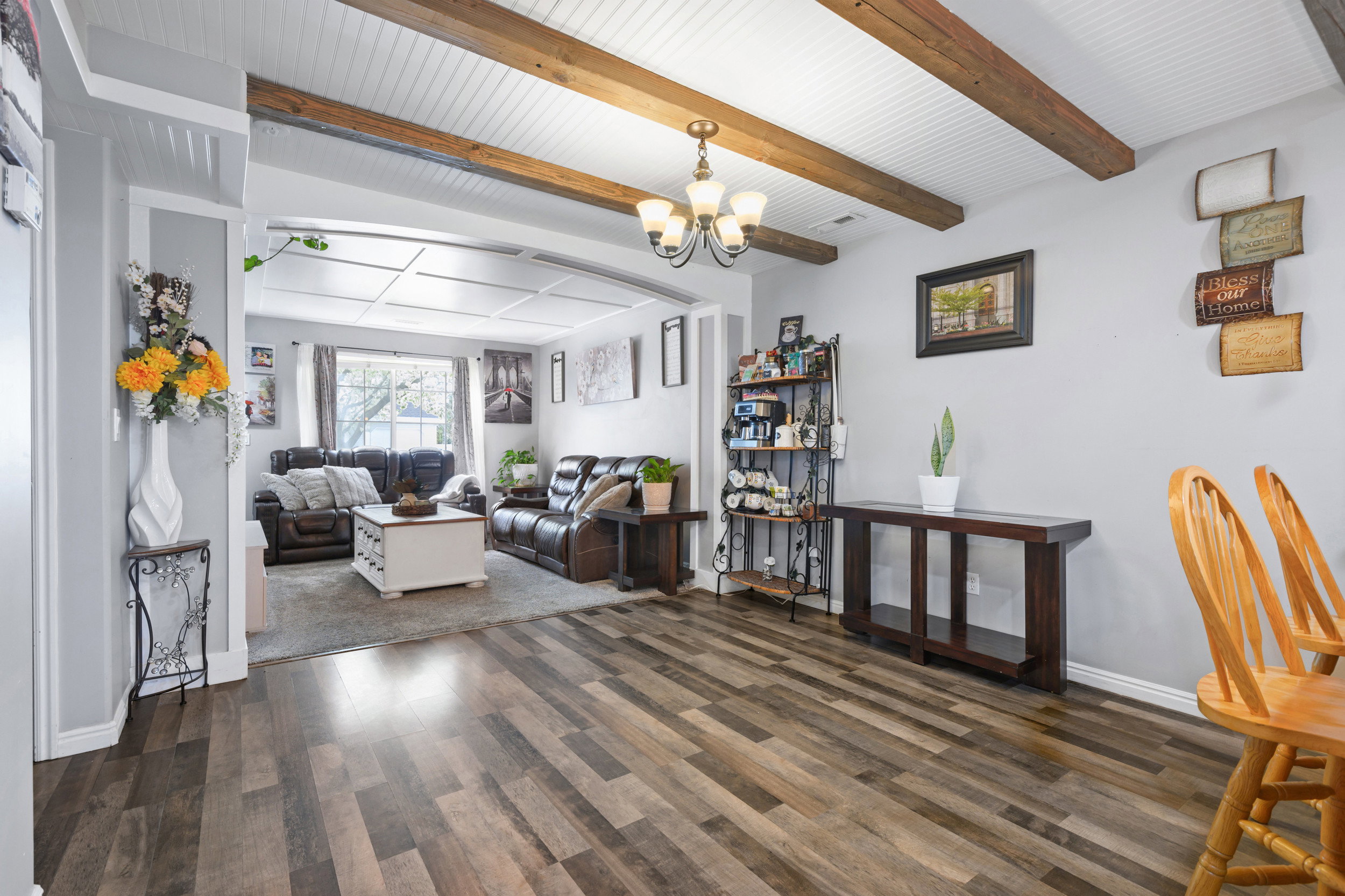 Living area featuring a chandelier, dark wood finished floors, and beamed ceiling