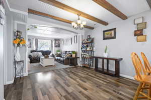 Living area featuring a chandelier, dark wood finished floors, and beamed ceiling