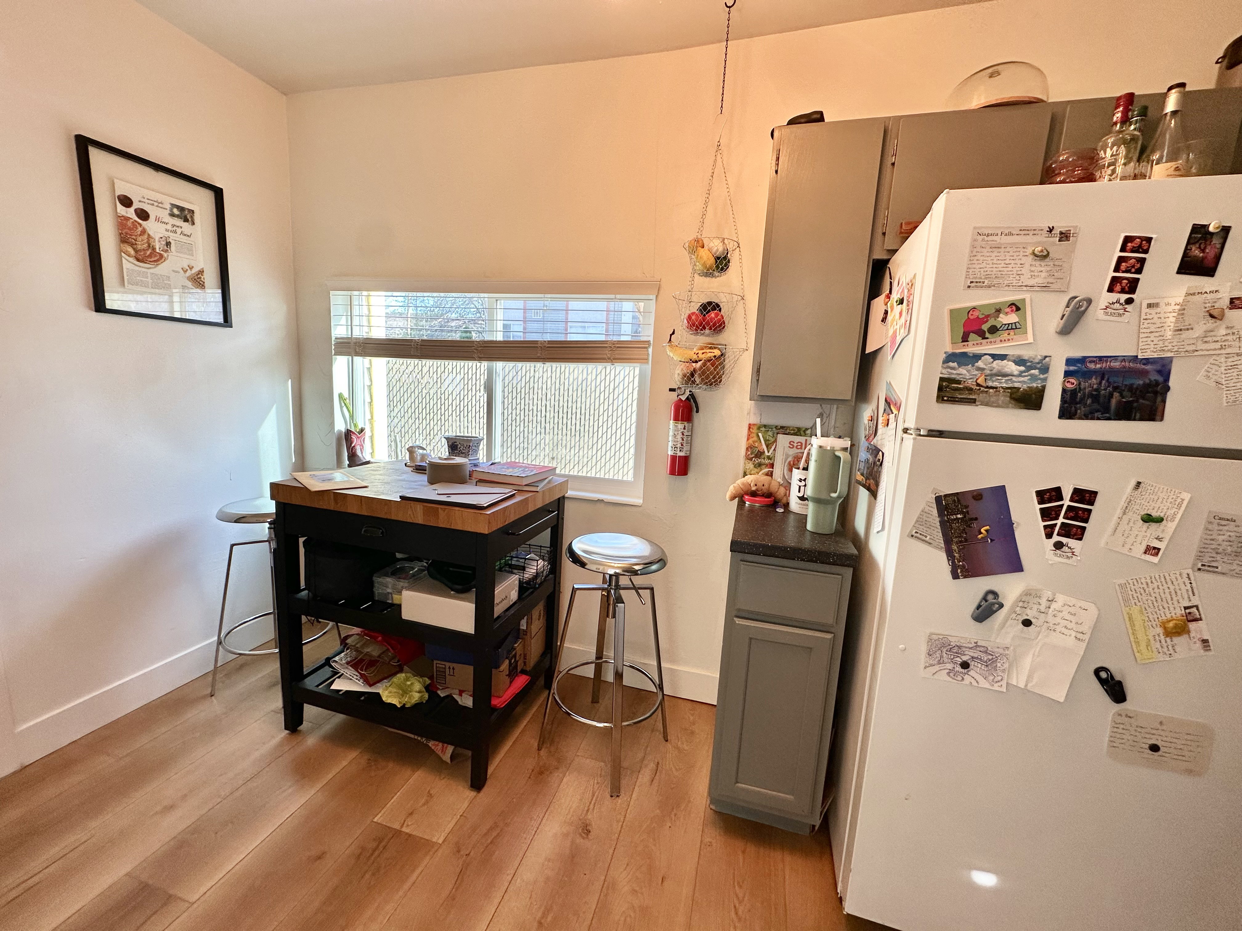 Kitchen with freestanding refrigerator, dark countertops, gray cabinets, and light wood-type flooring
