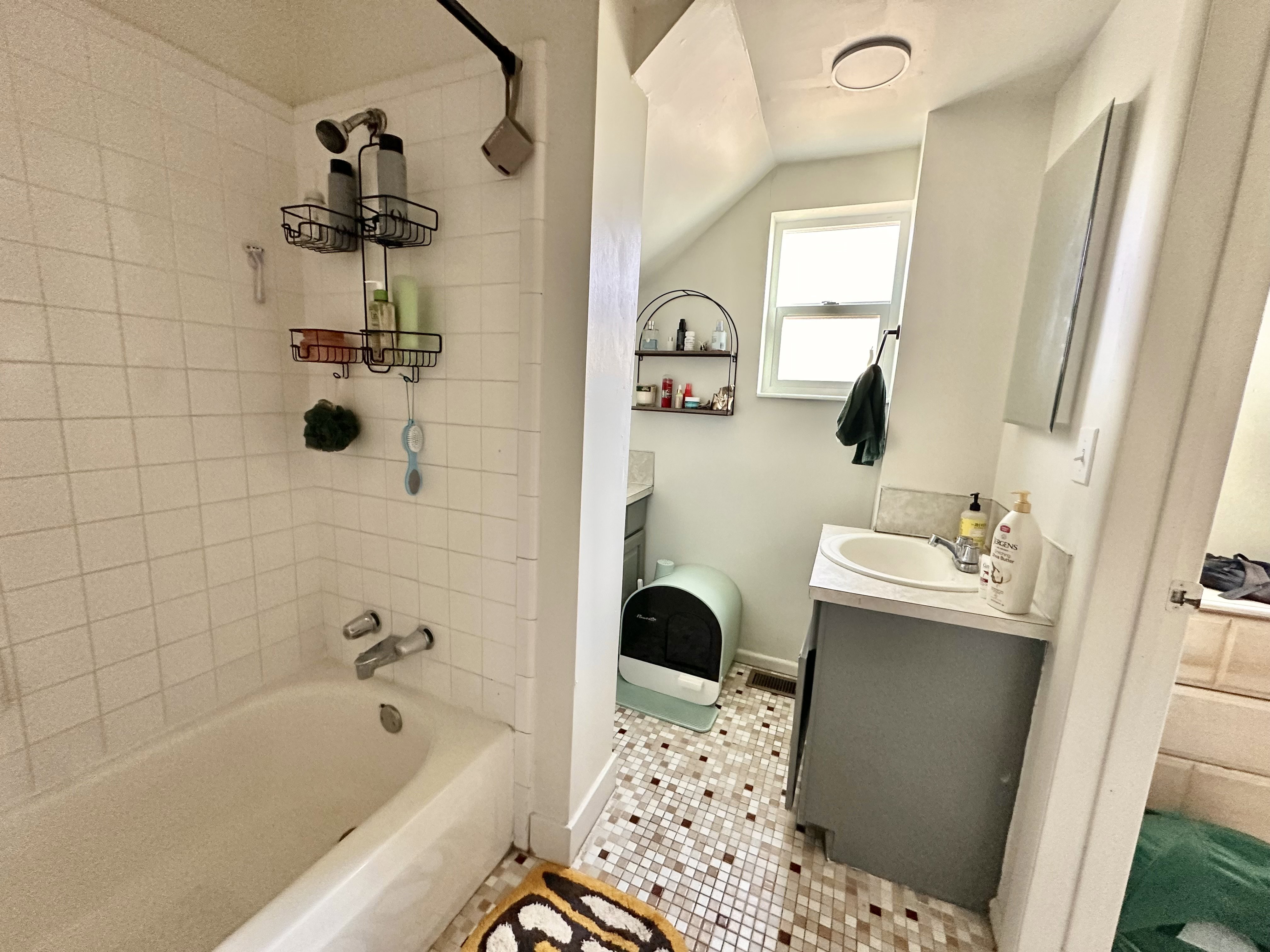 Full bath featuring vanity, shower / bathtub combination, light tile patterned flooring, and vaulted ceiling