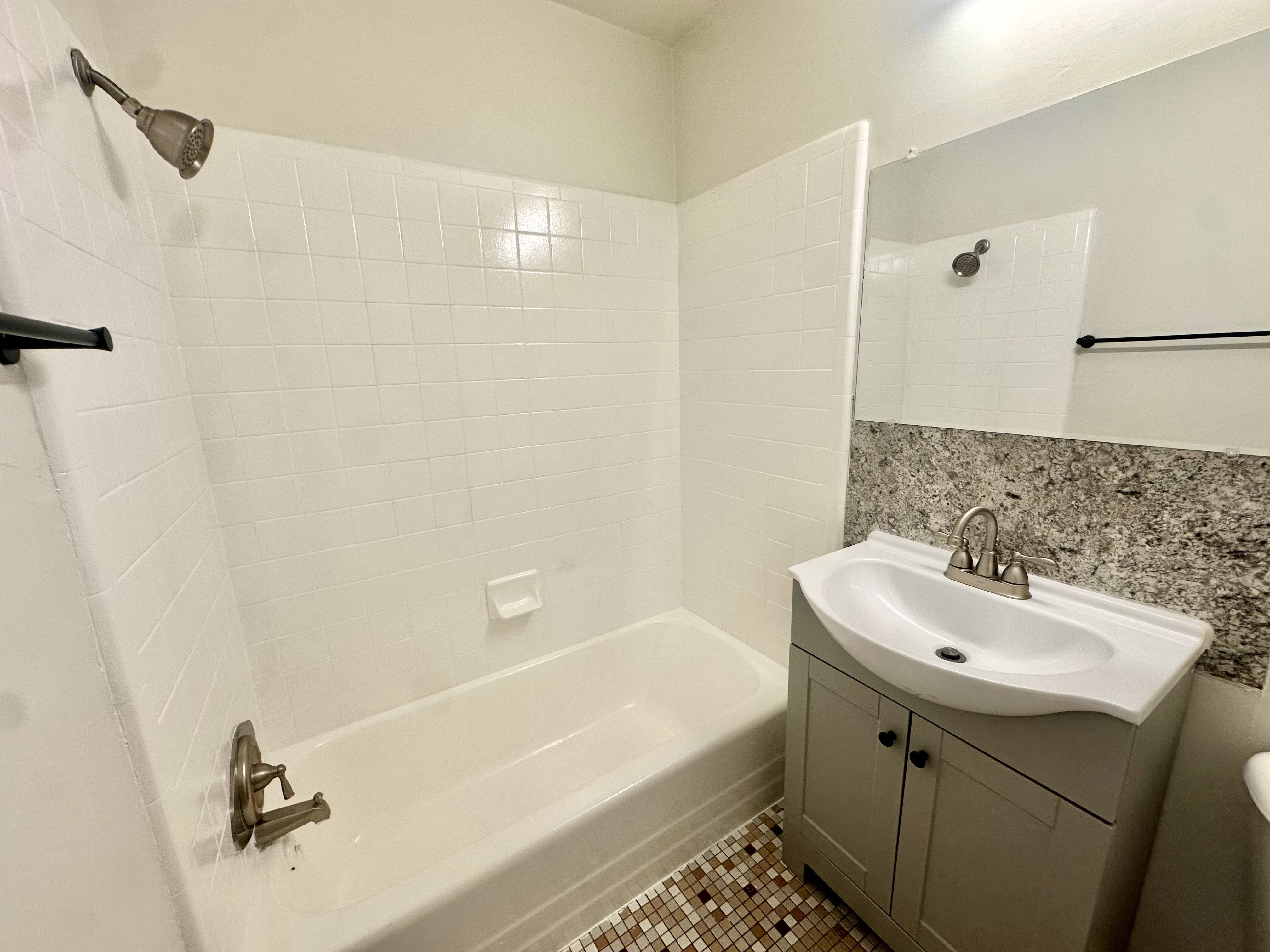 Bathroom featuring a white bathtub and shower with white subway tile surround