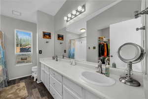 Bathroom with double vanity, dark wood-style floors, and a walk in closet