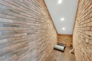 Corridor featuring lofted ceiling, brick wall, and recessed lighting