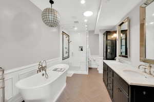 Bathroom featuring wainscoting, a stall shower, a soaking tub, parquet floors, and double vanity
