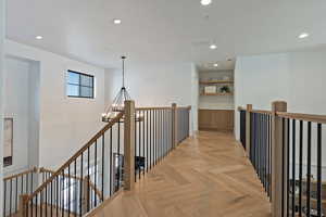 Hallway featuring an upstairs landing, suspended lighting, and parquet floors