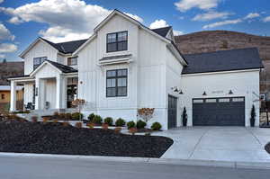 Modern inspired farmhouse featuring board and batten siding, roof with shingles, an attached garage, and driveway