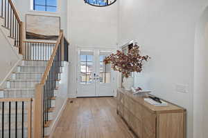 Entryway with french doors, light wood-type flooring, and a high ceiling