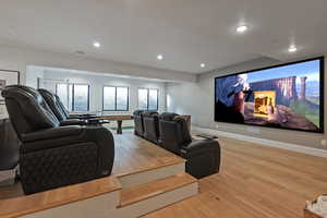 Cinema room with light wood-style floors and recessed lighting