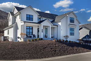 Modern farmhouse featuring board and batten siding, a porch, a standing seam roof, and roof with shingles