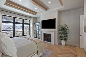 Bedroom featuring a raised ceiling, parquet floors, recessed lighting, beamed ceiling, and a lit fireplace