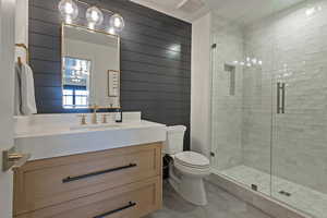 Bathroom featuring a stall shower, vanity, wooden walls, and light tile patterned flooring