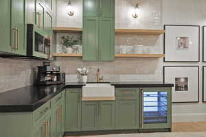 Kitchen featuring green cabinetry, wine cooler, and stainless steel microwave