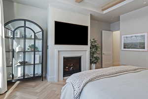 Bedroom featuring parquet flooring, a warm lit fireplace, and beam ceiling