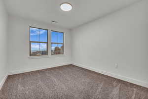 Empty room featuring baseboards and dark colored carpet
