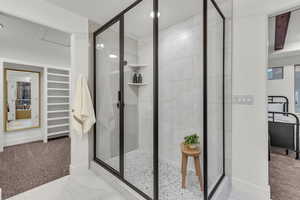 Full bath featuring light carpet, a shower stall, and a walk in closet