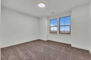 Unfurnished room with baseboards and dark carpet