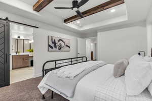 Carpeted bedroom featuring a barn door, recessed lighting, ensuite bath, a ceiling fan, and beam ceiling