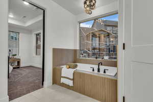 Full bathroom featuring a bath, light carpet, and a tray ceiling