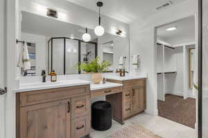 Full bathroom with double vanity, light colored carpet, a stall shower, a spacious closet, and light tile patterned floors