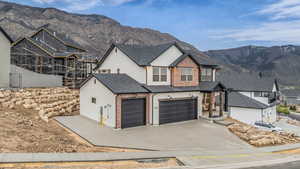 View of front of house featuring a mountain view, concrete driveway, a garage, and stucco siding
