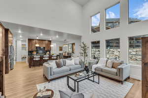 Living room featuring light wood-style floors, recessed lighting, and a high ceiling